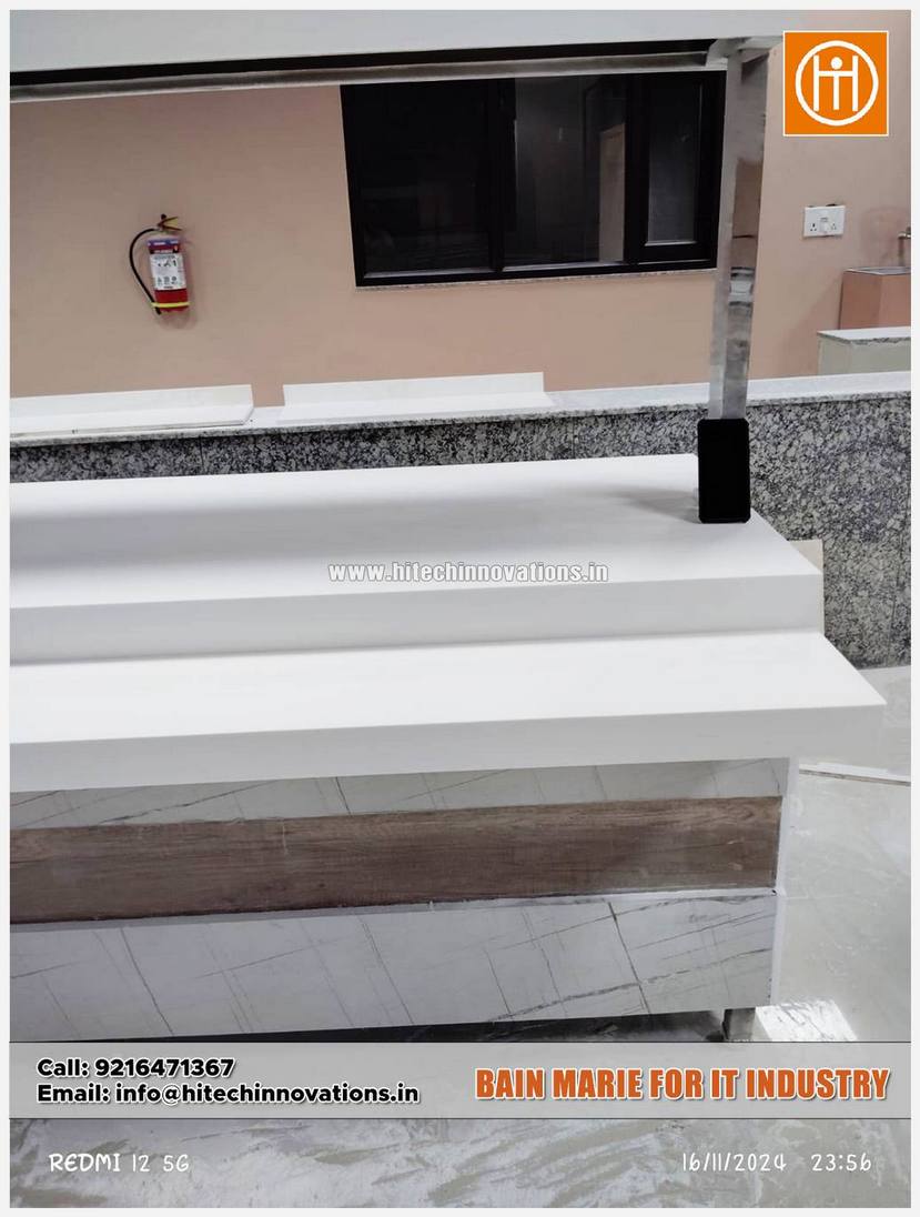 Detail shot of the side profile of a Bain-Marie station, highlighting the wood-grain and marble decorative paneling against the solid white countertop