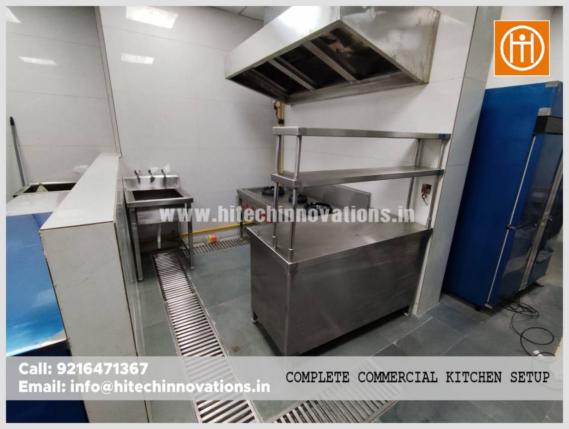 Stainless steel food preparation island with integrated shelving and commercial exhaust system installed by Hitech Innovations in a Haryana IT office.