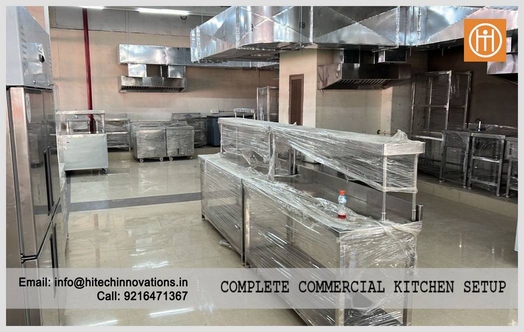 Wide view of the complete stainless steel kitchen installation including preparation areas and ventilation systems.