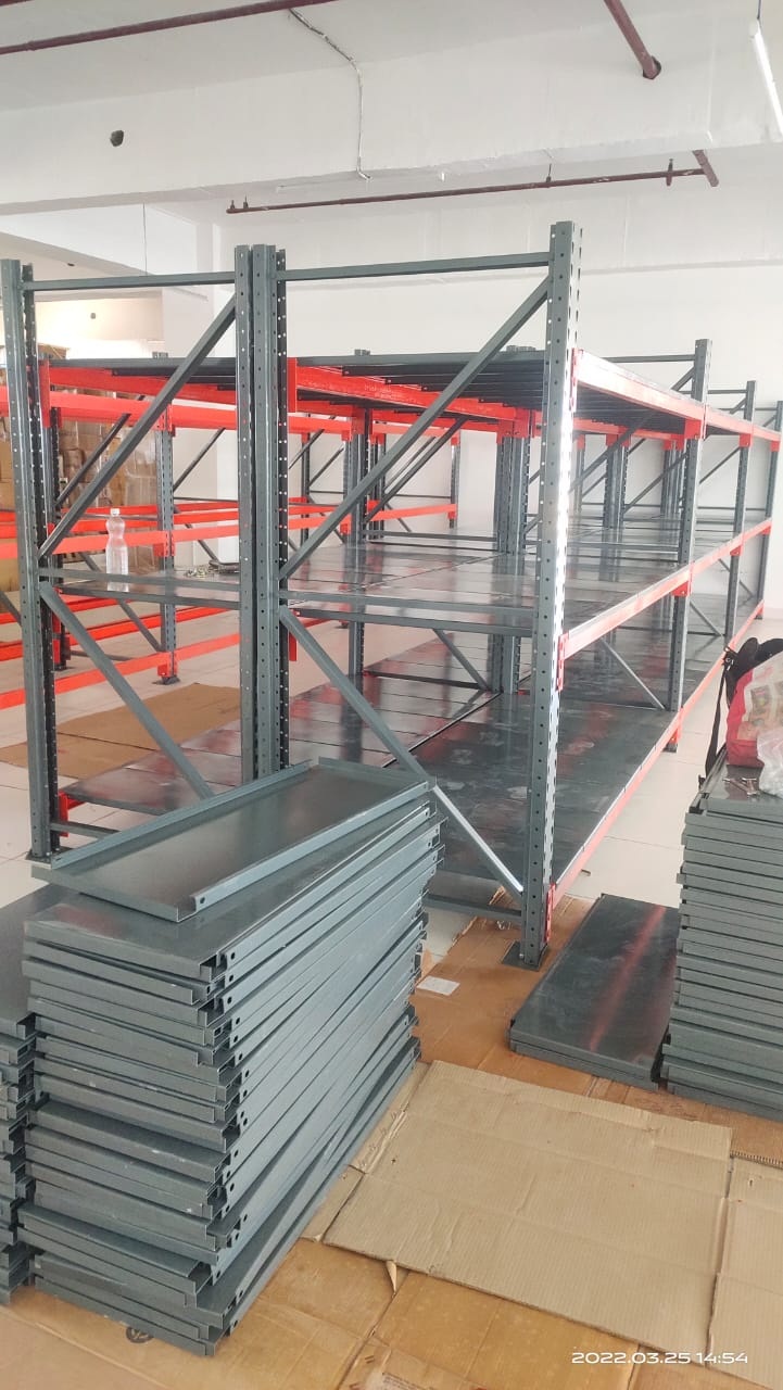 Industrial grey and orange heavy-duty warehouse racking system being assembled with stacked metal shelves in a clean storage facility.