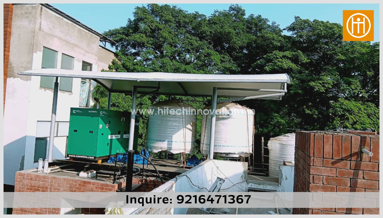 A white curved tensile shade structure by Hitech Innovations installed on a rooftop to provide weather protection for a green Cummins power generator and two large water tanks.