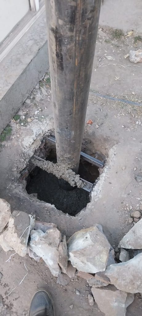 Hitech Innovations crew securing a structural steel pillar into a reinforced concrete foundation for a durable car parking shed.