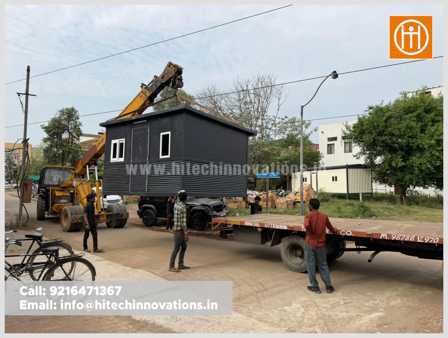 Industrial crane suspending a prefabricated guard room in the air during the loading process for delivery to Baddi.