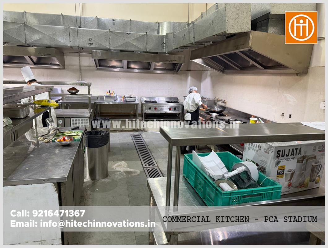 Hitech Innovations industrial kitchen installation showing stainless steel prep tables, commercial burners, and large galvanized air ducting at PCA Stadium Mullanpur.