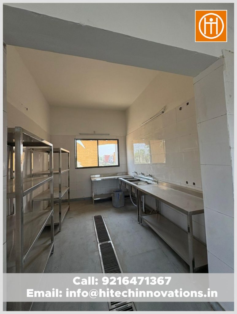 Heavy-gauge stainless steel sinks, storage racks, and integrated floor drainage system in a professional kitchen.