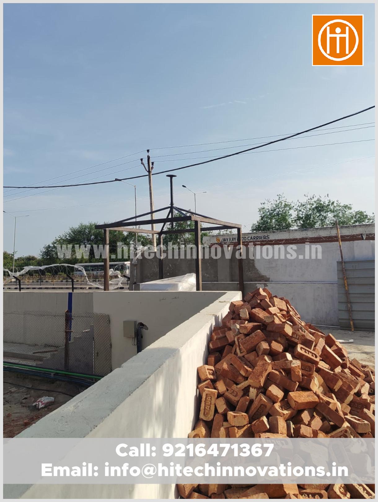 Construction site progress showing the structural steel base of a security gazebo with bricks in the foreground.
