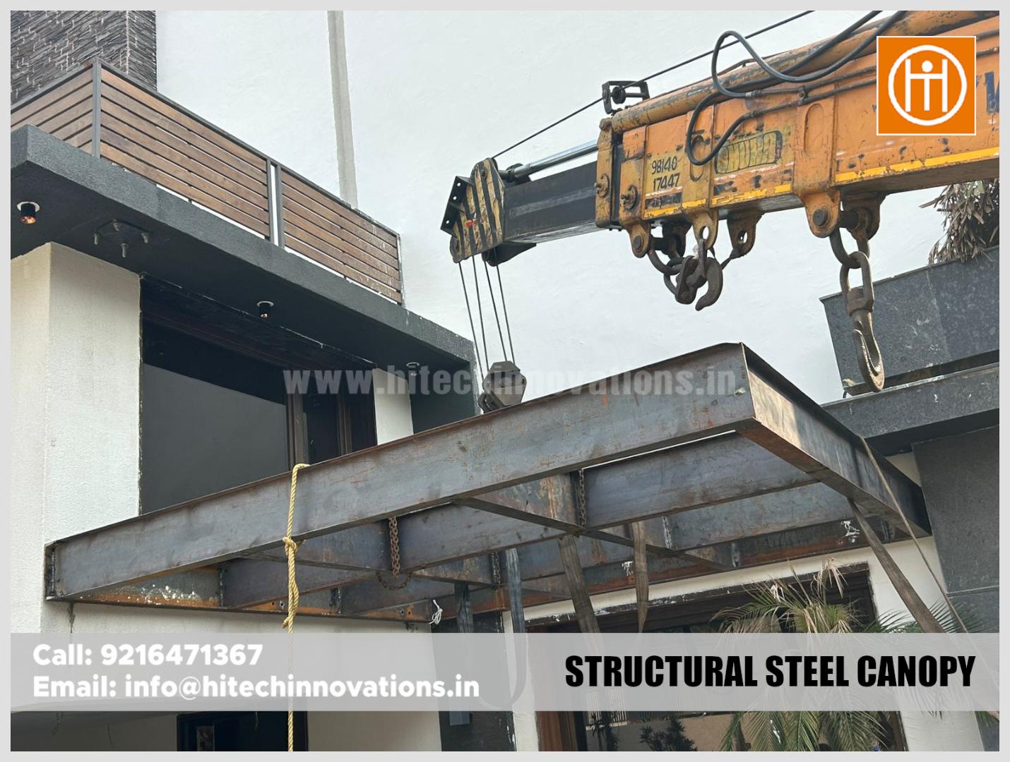 A heavy-duty crane lifting a steel canopy frame during installation.
