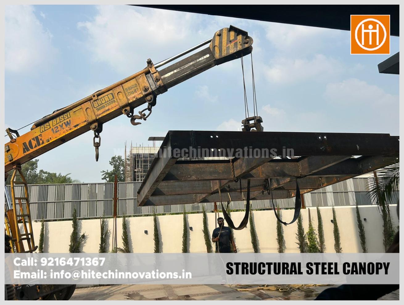 Close-up of a steel canopy frame being hoisted into position by a professional crane operator.