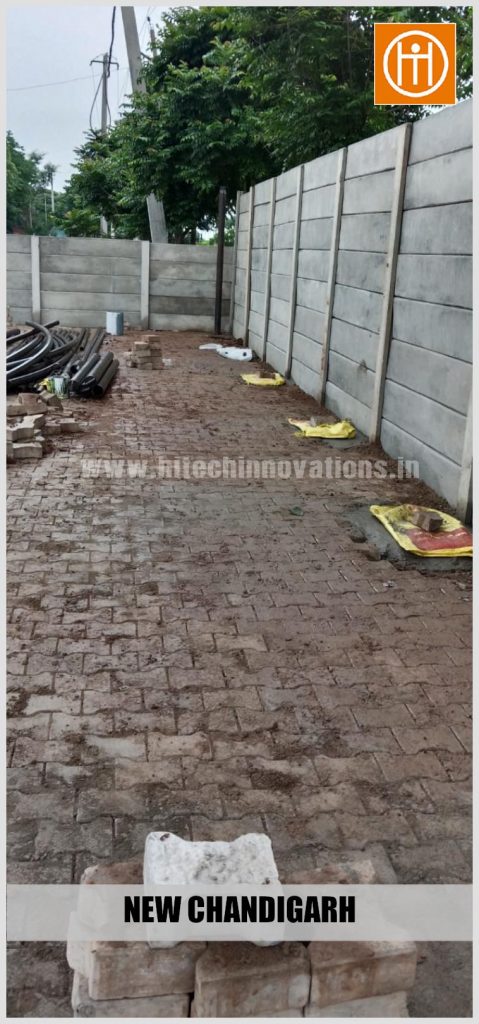 View of drainage pipes and site materials organized near the precast boundary wall during early groundwork stages.