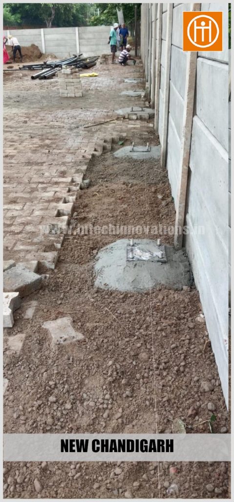 Close-up of newly cast concrete foundation pedestals with embedded anchor bolts for the structural steel columns.