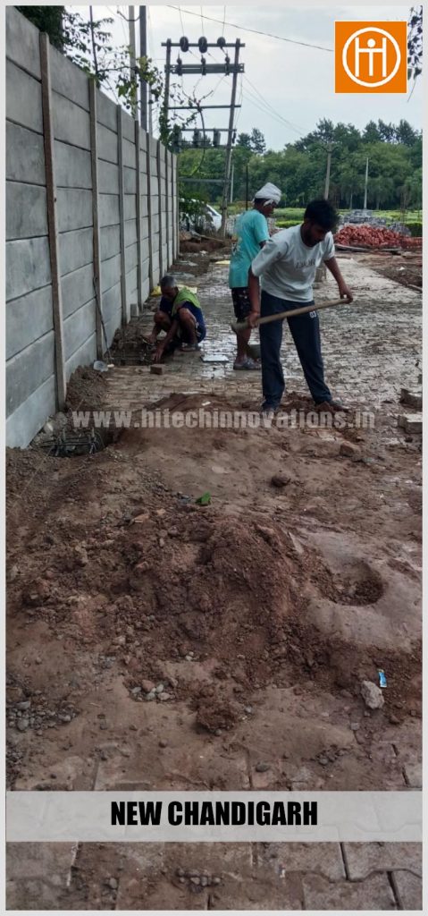 Construction crew leveling soil and excavating anchor foundation pits for the upcoming vehicle shed structure.