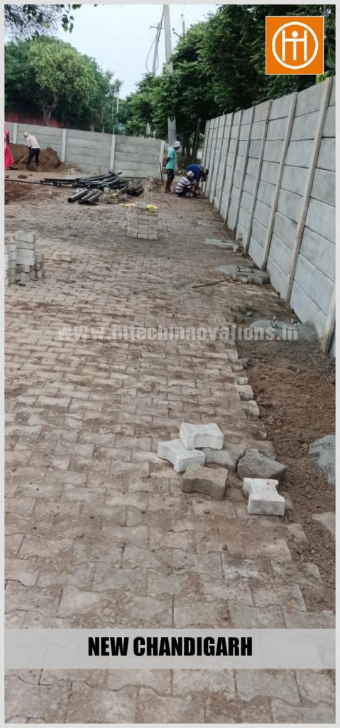 Wide view of the paved courtyard area with stacked interlocking bricks and foundation mounting points.