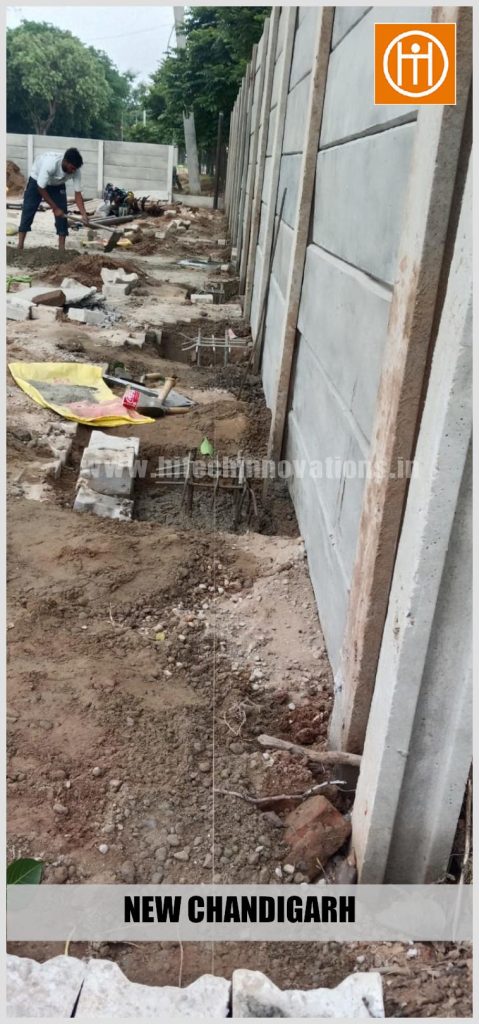 Excavated footing pits with steel rebar reinforcement cages ready for concrete pouring near the boundary fenc