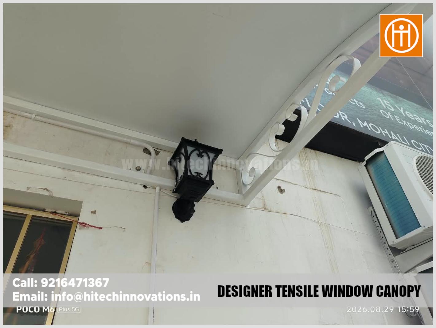 Detailed view of the decorative metal scrollwork bracket and attached vintage wall lamp on a tensile canopy structure