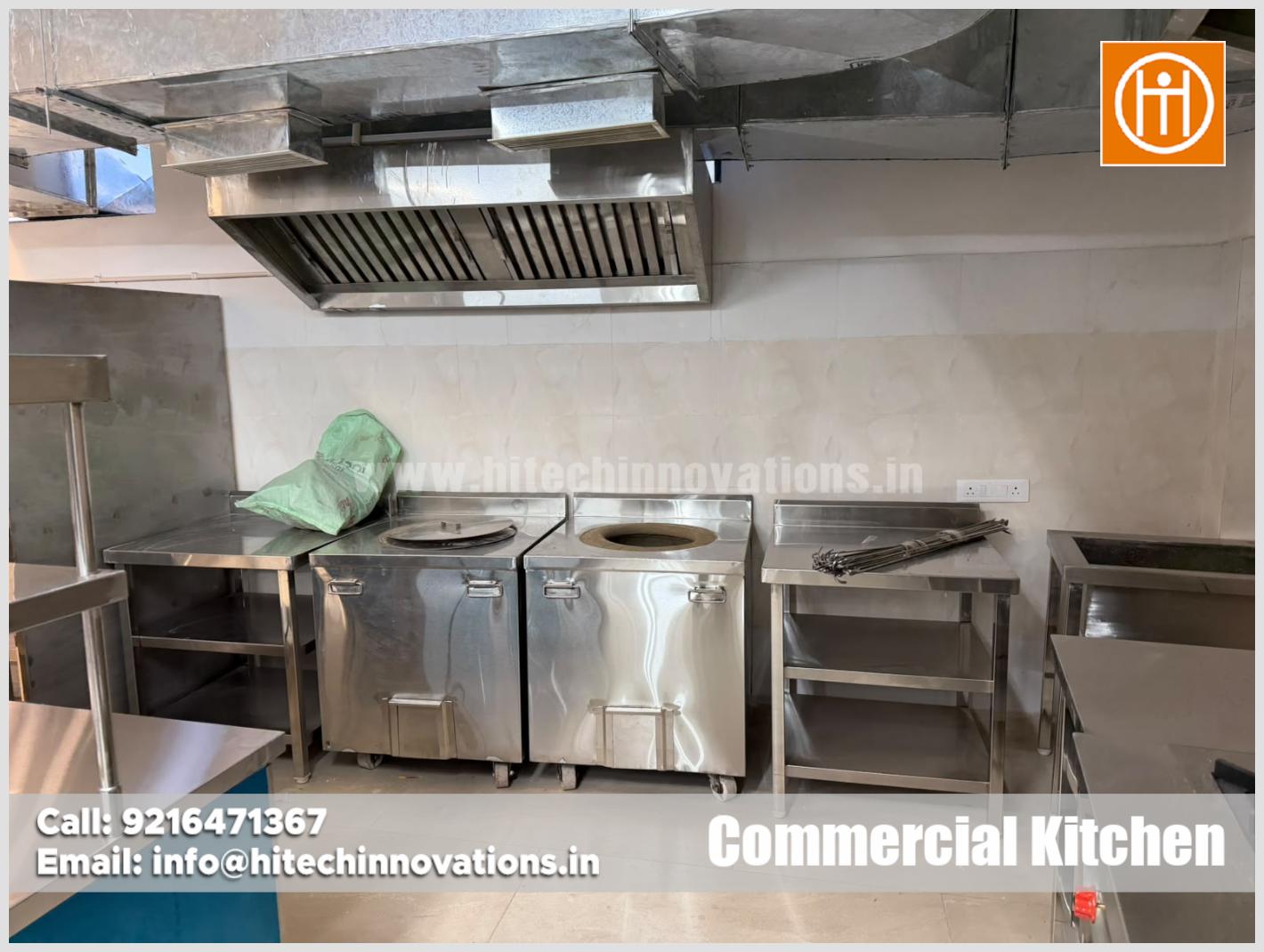Stainless steel commercial clay tandoors with preparation tables, skewer storage, and dedicated exhaust hood in hotel kitchen